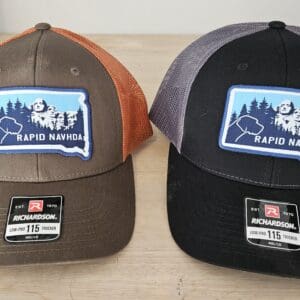 Rapid NAVHDA trucker hats with South Dakota patch logo in brown and orange and black and gray Richardson 115 hats on display.